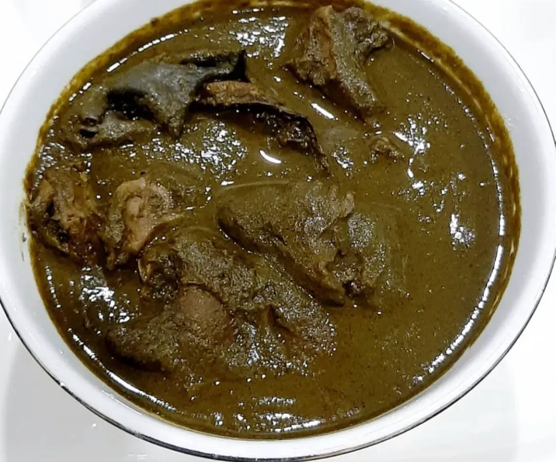 Edo Black Soup, a Nigerian soup of ground bitter leaf, scent leaf and uziza, served with pounded yam